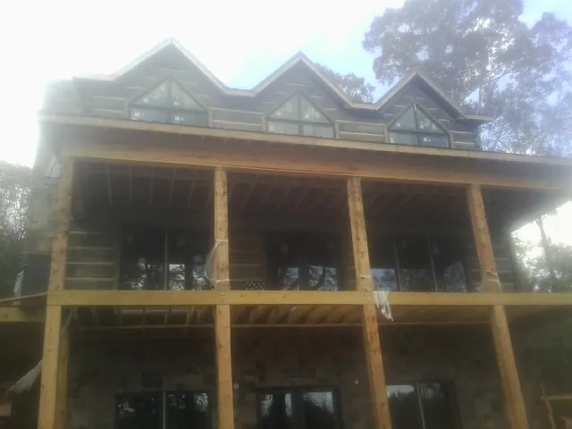 Dormers and porch framing on a large log home under construction — Roof Coating work by our crew in Marina