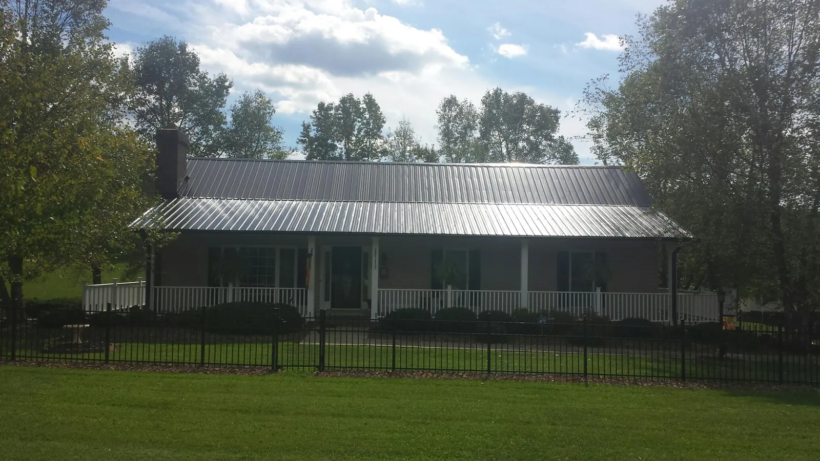 Gray metal roof on a brick ranch with a full width front porch — Gutter Guard Installation work by our crew in Marina
