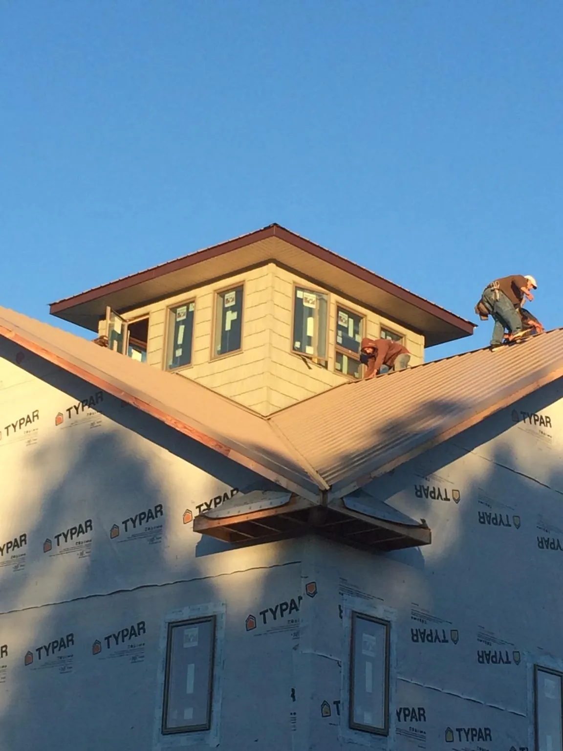 Roofers working around a rooftop cupola on a new metal roof at sunset — Roof Waterproofing in Marina by Roofing Brothers